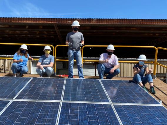 5 students standing at the top of a solar panel project 